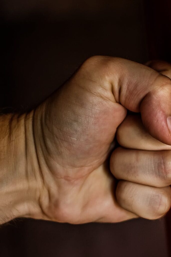 A detailed close-up of a clenched fist striking a red surface showcasing strength.